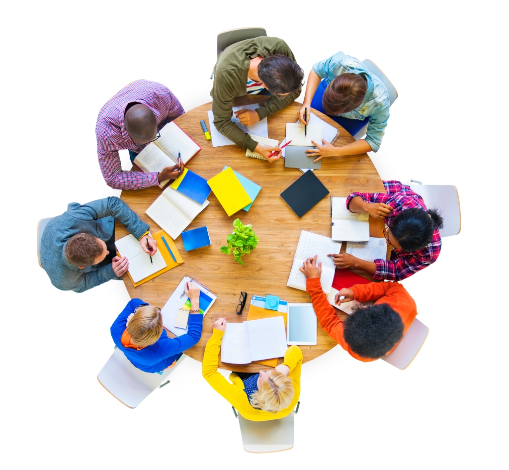 Overhead photograph of a group of eight students with diverse physical appearances seated around a round table studying together.